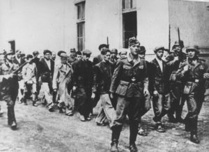 German troops are marching over 2000 Serbian hostages out of the city to be shot- among them 300 16-18 year old boys from local high school: Serbian teacher Miloje Pavlovic asks the Germans to shoot him instead of one of the teenagers taken hostage- they refuse. Miloje then volunteers to be shot alongside his pupils.