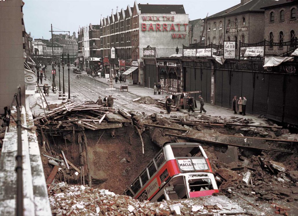 A London bus has plunged headlong into the huge bomb crater outside Balham Tube Station- in dark of the nightly blackout, bus driver didn't see it.The bus is being removed from the Balham Underground station bomb crater with a crane- amazingly, no passengers were seriously hurt by the crash