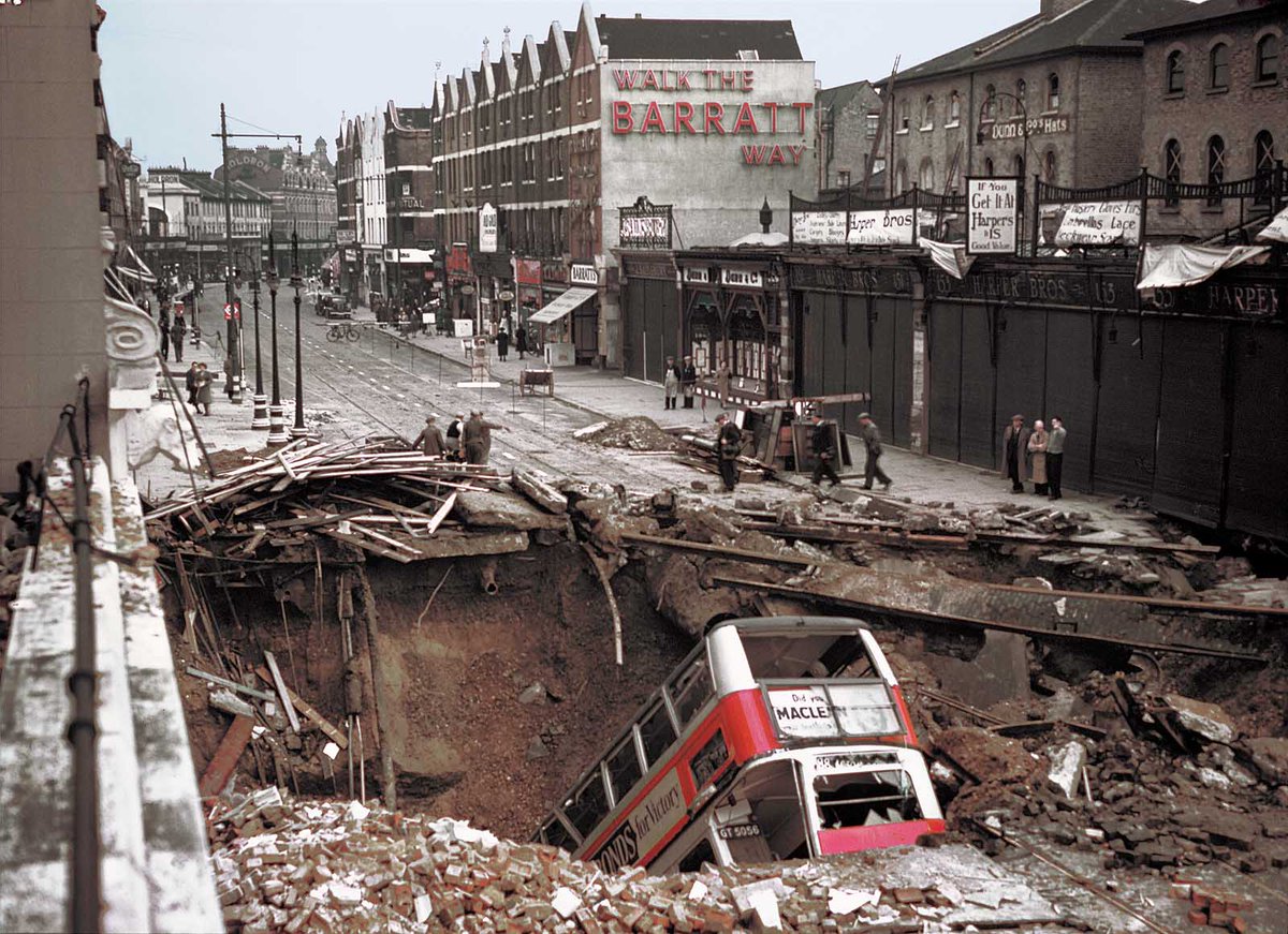 A London bus has plunged headlong into the huge bomb crater outside Balham Tube Station- in dark of the nightly blackout, bus driver didn't see it.The bus is being removed from the Balham Underground station bomb crater with a crane- amazingly, no passengers were seriously hurt by the crash