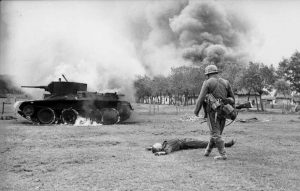 A German infantryman walks toward the body of a killed Soviet soldier and a burning BT-7 light tank in the southern Soviet Union in in 1941, during the early days of Operation Barbarossa.