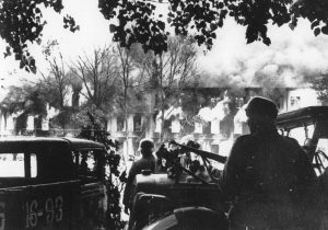Flames shoot high from burning buildings in the background as German troops enter the city of Smolensk, in the central Soviet Union, during their offensive drive onto the capital Moscow, in August of 1941.