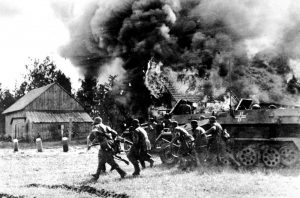 German soldiers, supported by armored personnel carriers, move into a burning Russian village at an unknown location during the German invasion of the Soviet Union, on June 26, 1941