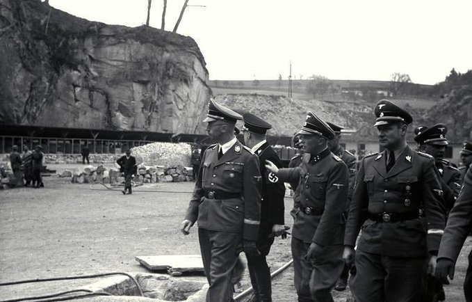 For Himmler's inspection, SS Einsatzgruppe B pick 100 Jews from Minsk to be shot. Among them, Himmler spots a young blond boy. Himmler: "Are you sure you're a Jew?" Boy: "Yes." "You have no Aryan ancestors?" "No." "Then I can't help- I did all I could." All shot.Karl Wolff, Himmler's adjutant (right), accompanies SS chief to mass shooting: "He'd never seen dead people before. He stood at the edge of the open grave- & got brains splashed on his face & coat." Himmler, pale & heaving, is shocked by brutality of mass killing. He orders research on more "humane" methods of execution, less traumatic to SS executioners.
